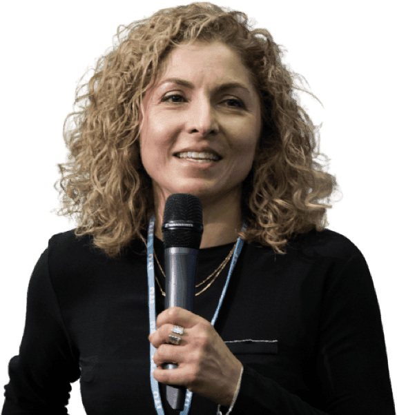 Anousheh Ansari: A woman with curly blond hair, holding a microphone close to her mouth and performing a presentation